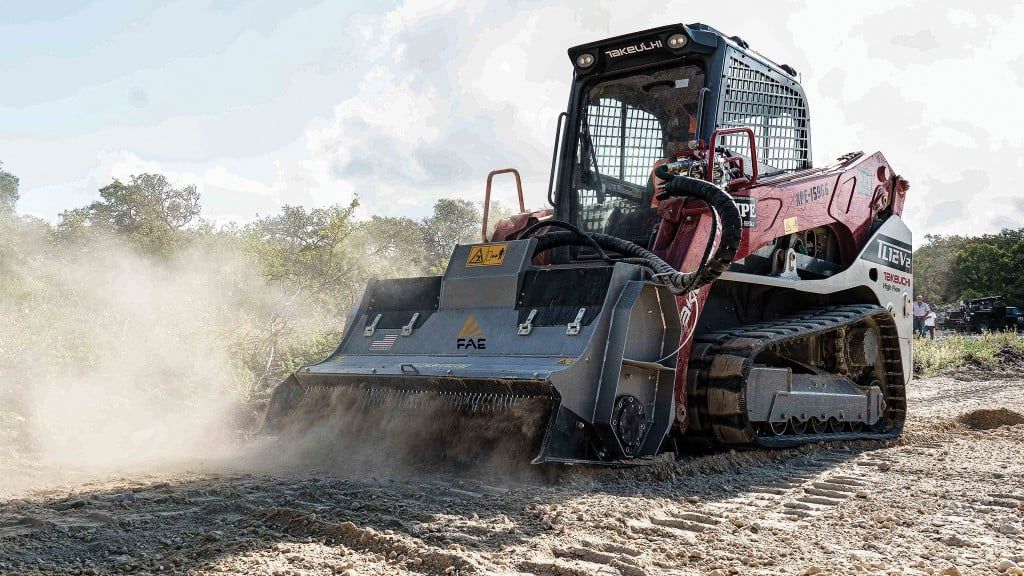 Compact track loader grading dry soil, kicking up dust at a construction site