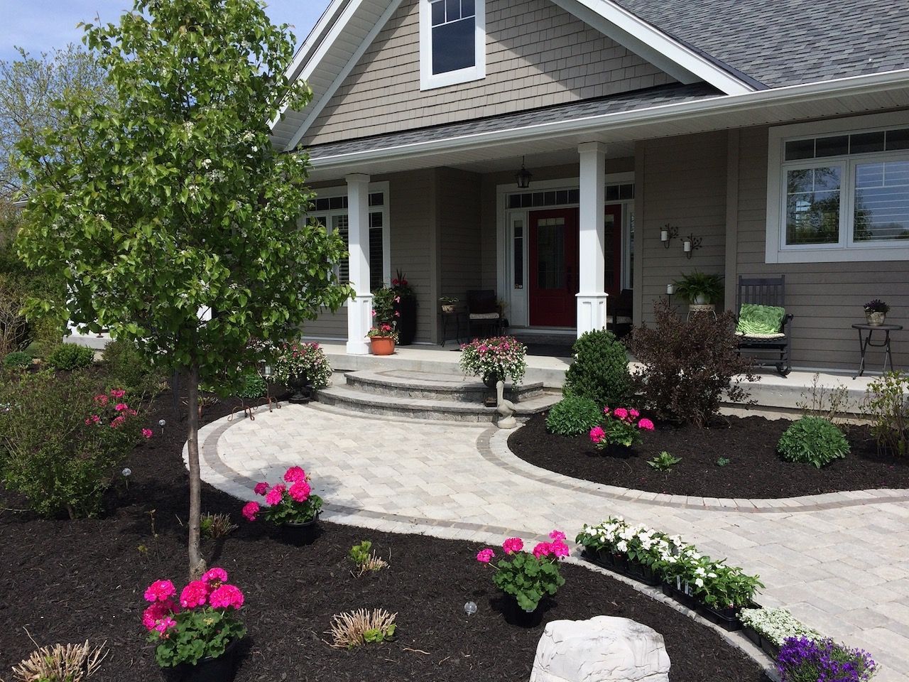 A house with a patio and flowers in front of it.
