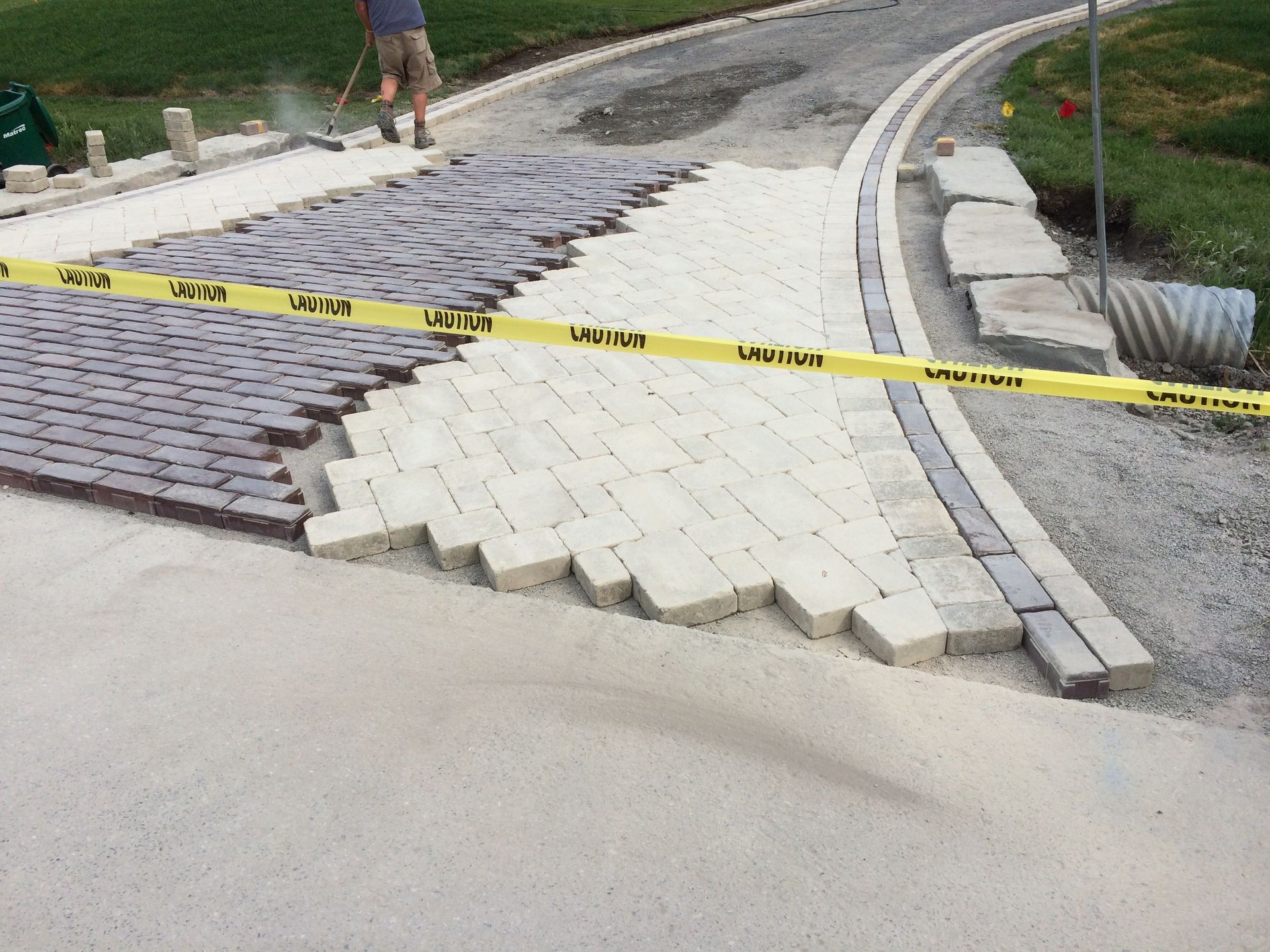 A man is working on a driveway with a yellow tape that says ' u.s.a. ' on it