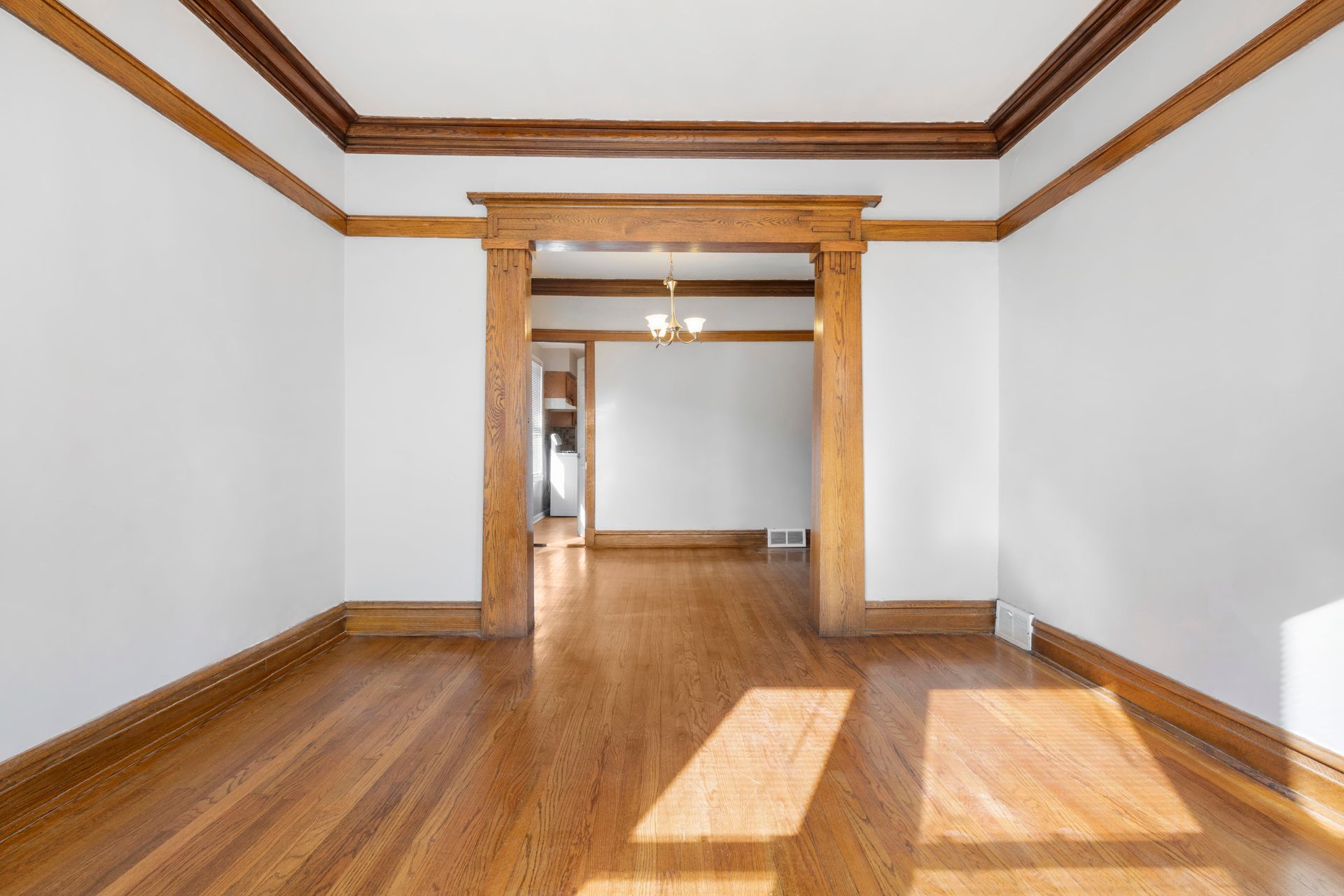 An empty room with hardwood floors and white walls