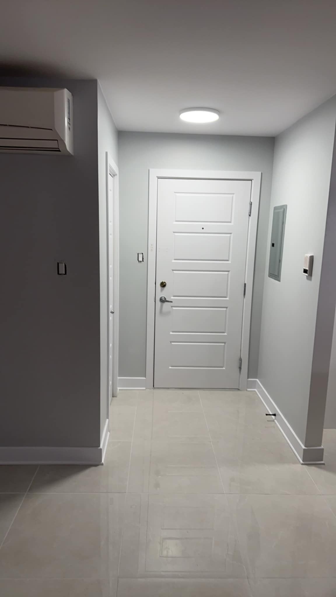Un couloir avec une porte blanche et une lumière au plafond.