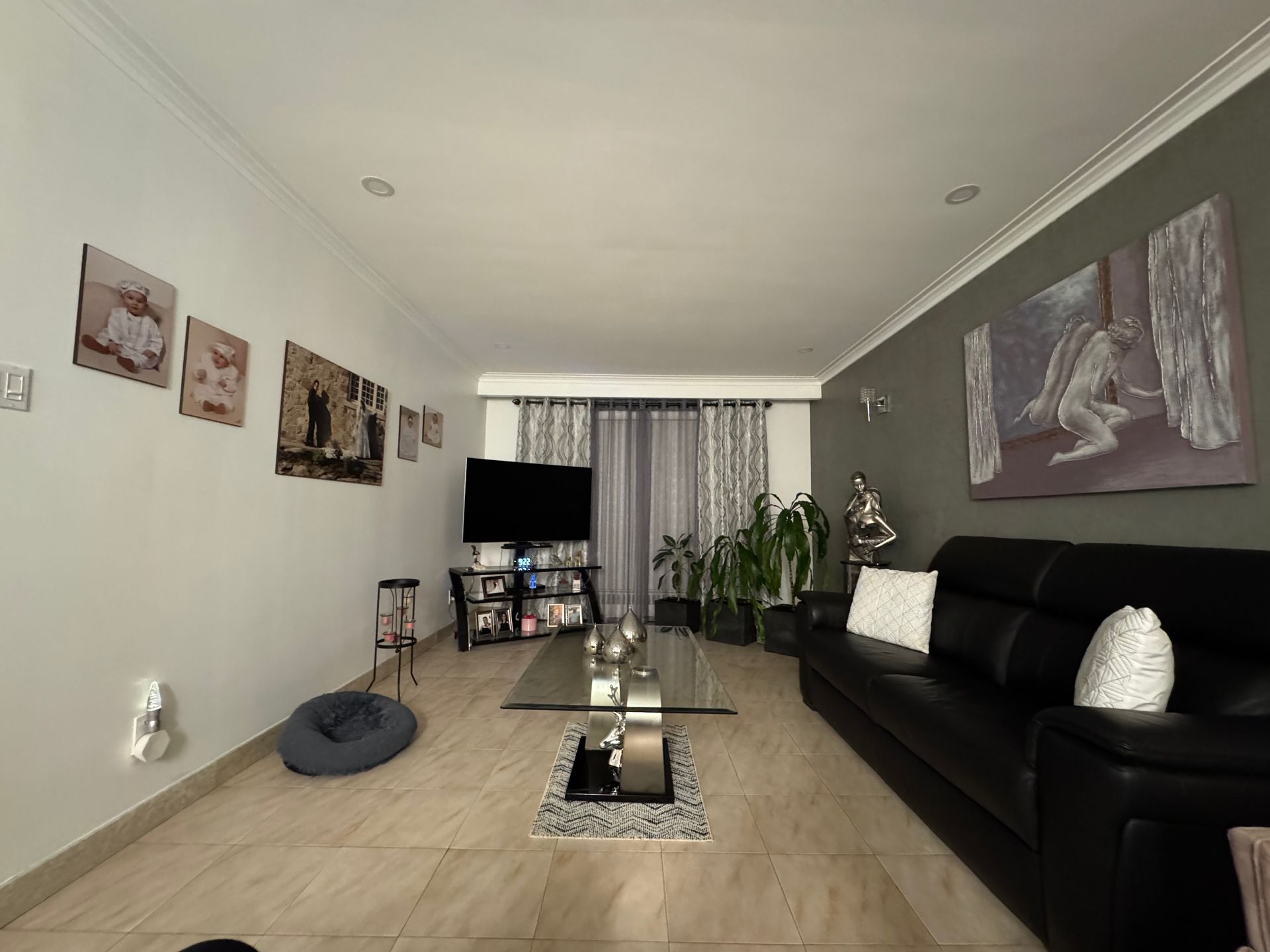 Un salon avec un canapé noir et une table basse en verre