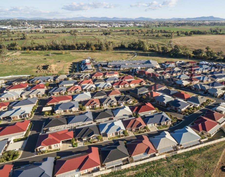 Aerial view of suburban houses with colourful roofs. A shopping centre and distant mountains are visible — L & K Electrical & Air Conditioning in Tamworth, NSW