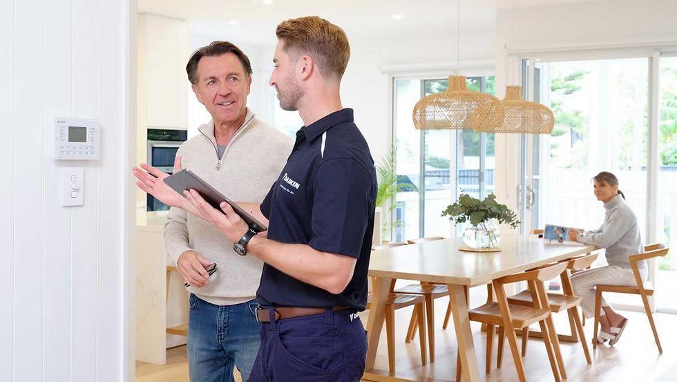 Man showing a digital tablet to another man in a bright living room; a woman works at the dining table — L & K Electrical & Air Conditioning in Gunnedah, NSW