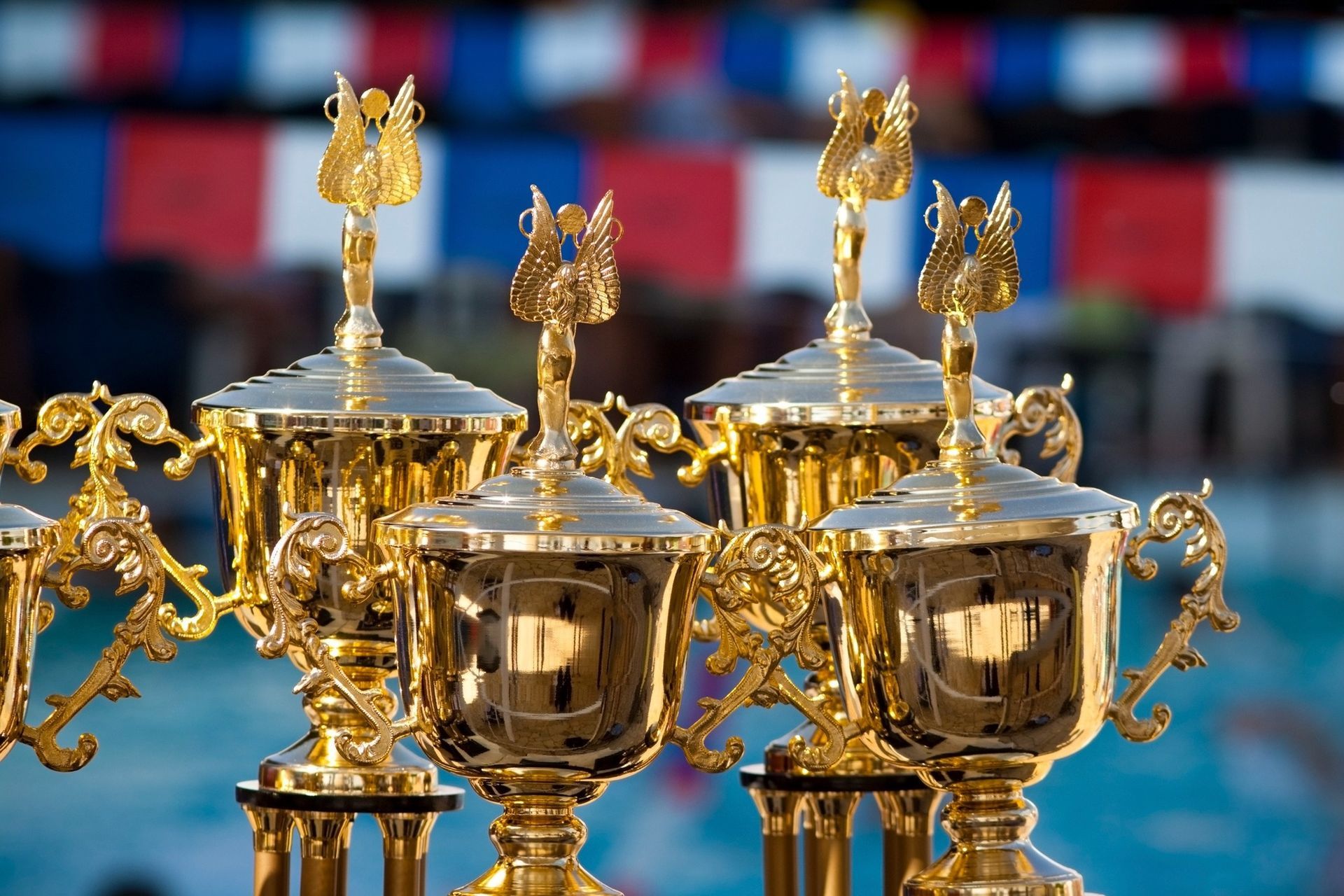 A bunch of gold trophies are lined up in a row