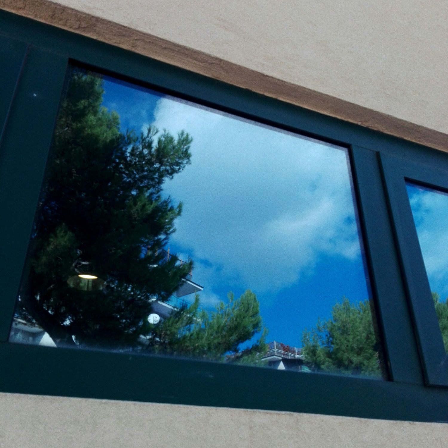 A window with a blue sky and trees reflected in it