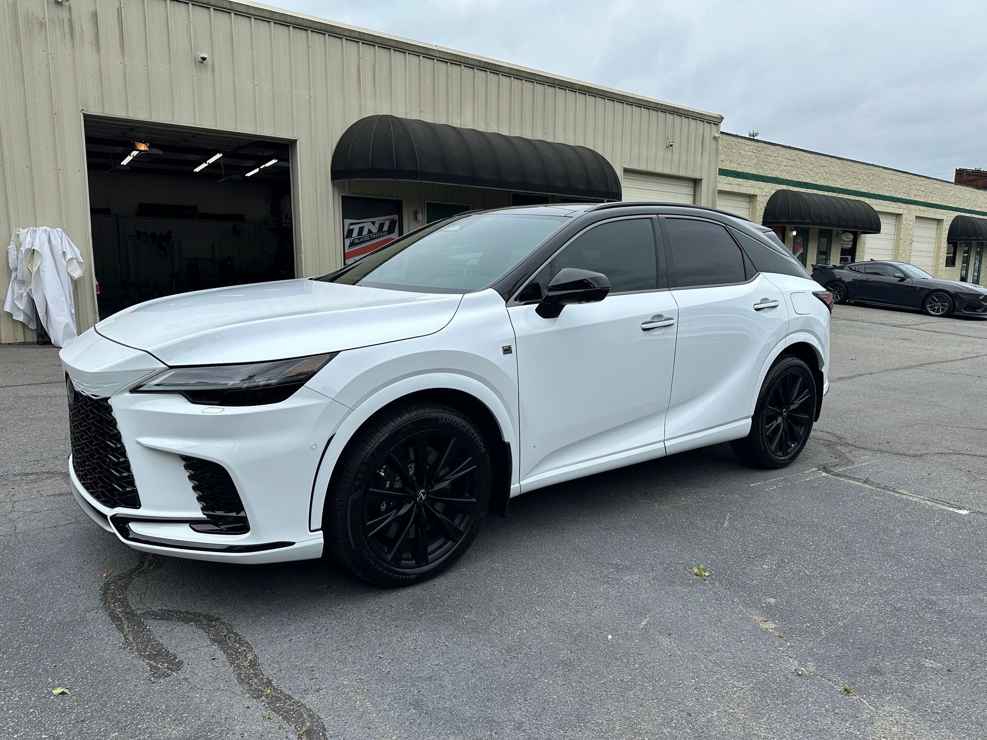 Two men are working on a white car in a garage.