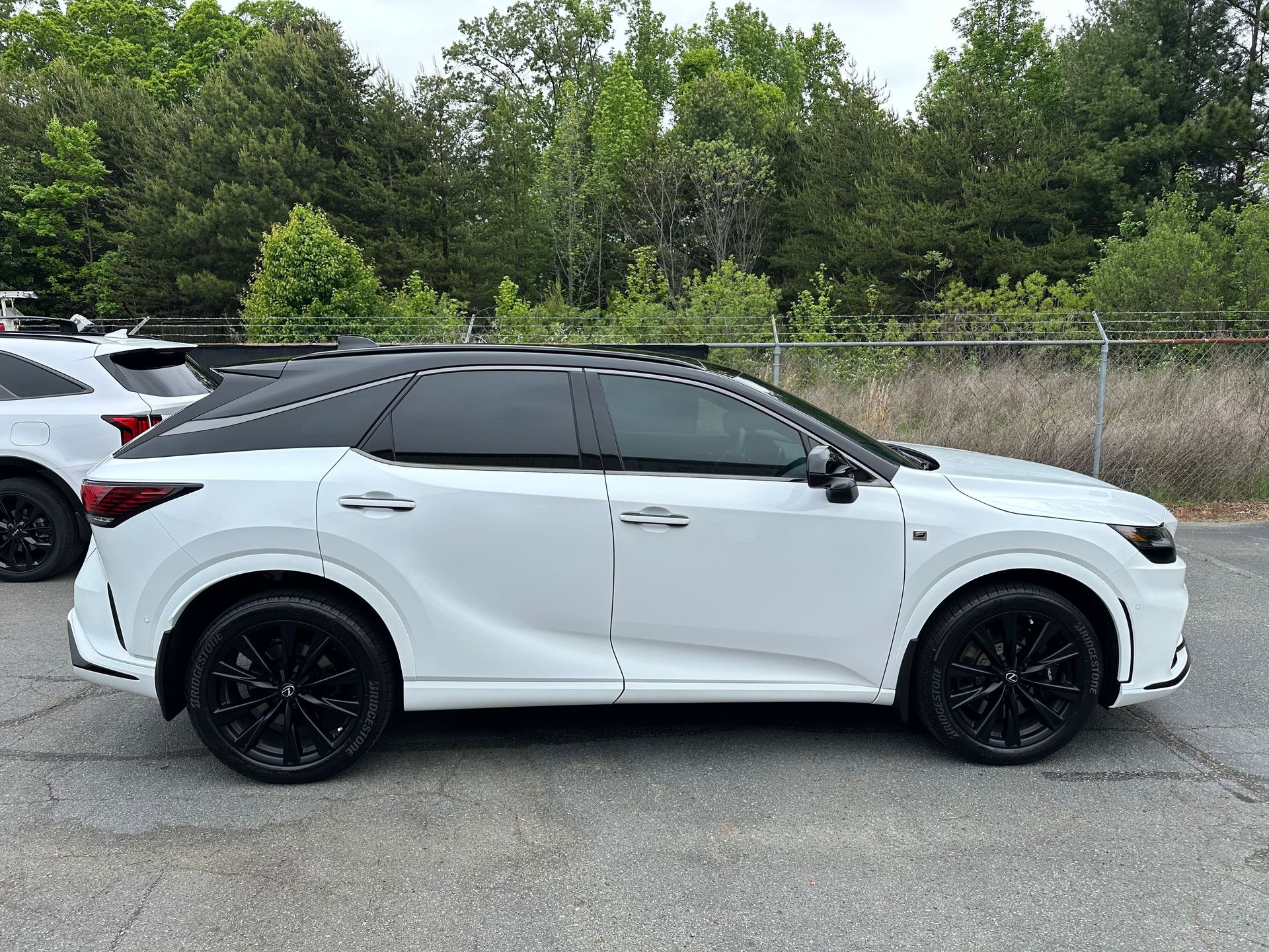 A white suv with black wheels is parked in a parking lot.