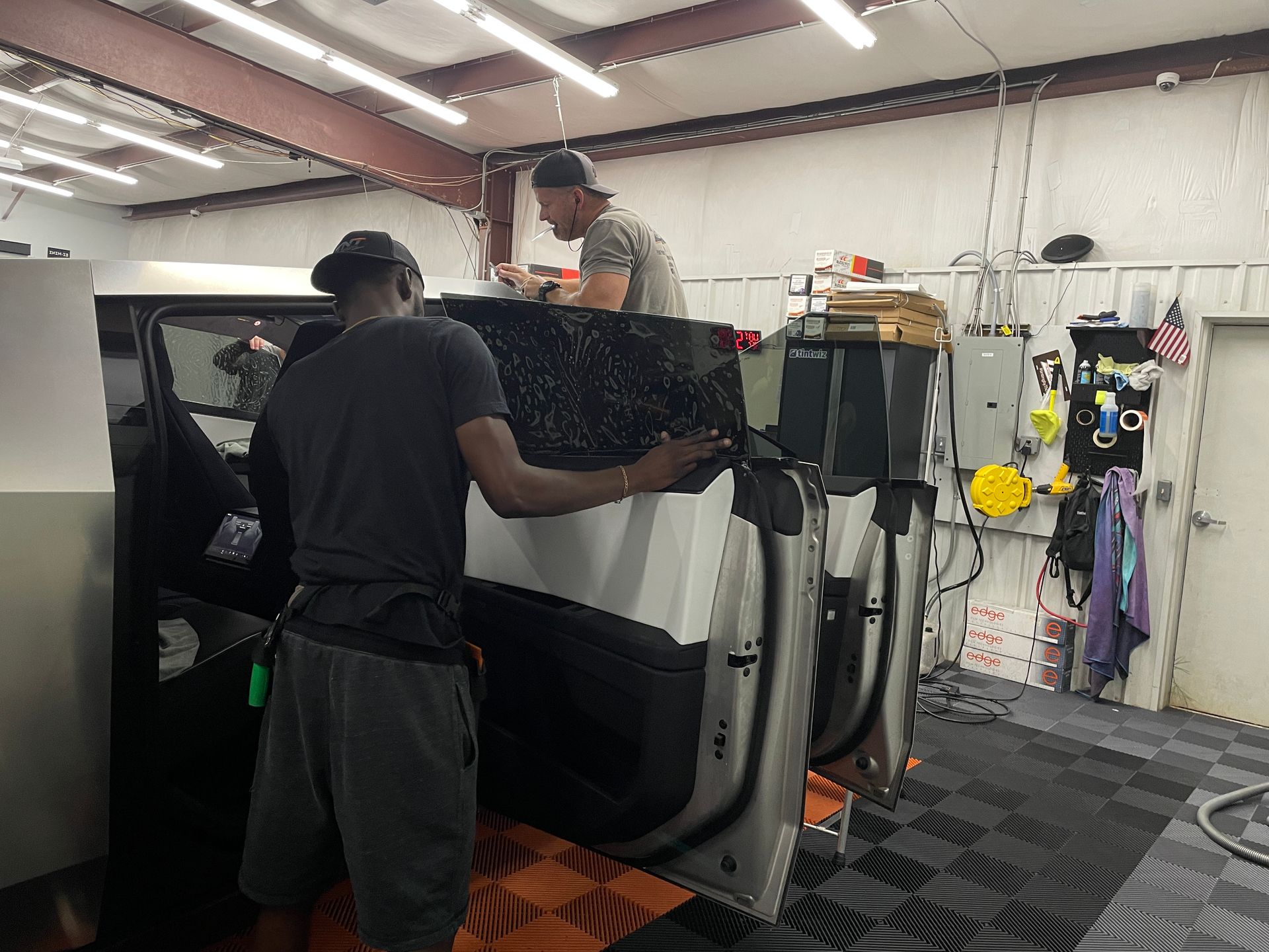 Two men are working on a car in a garage.