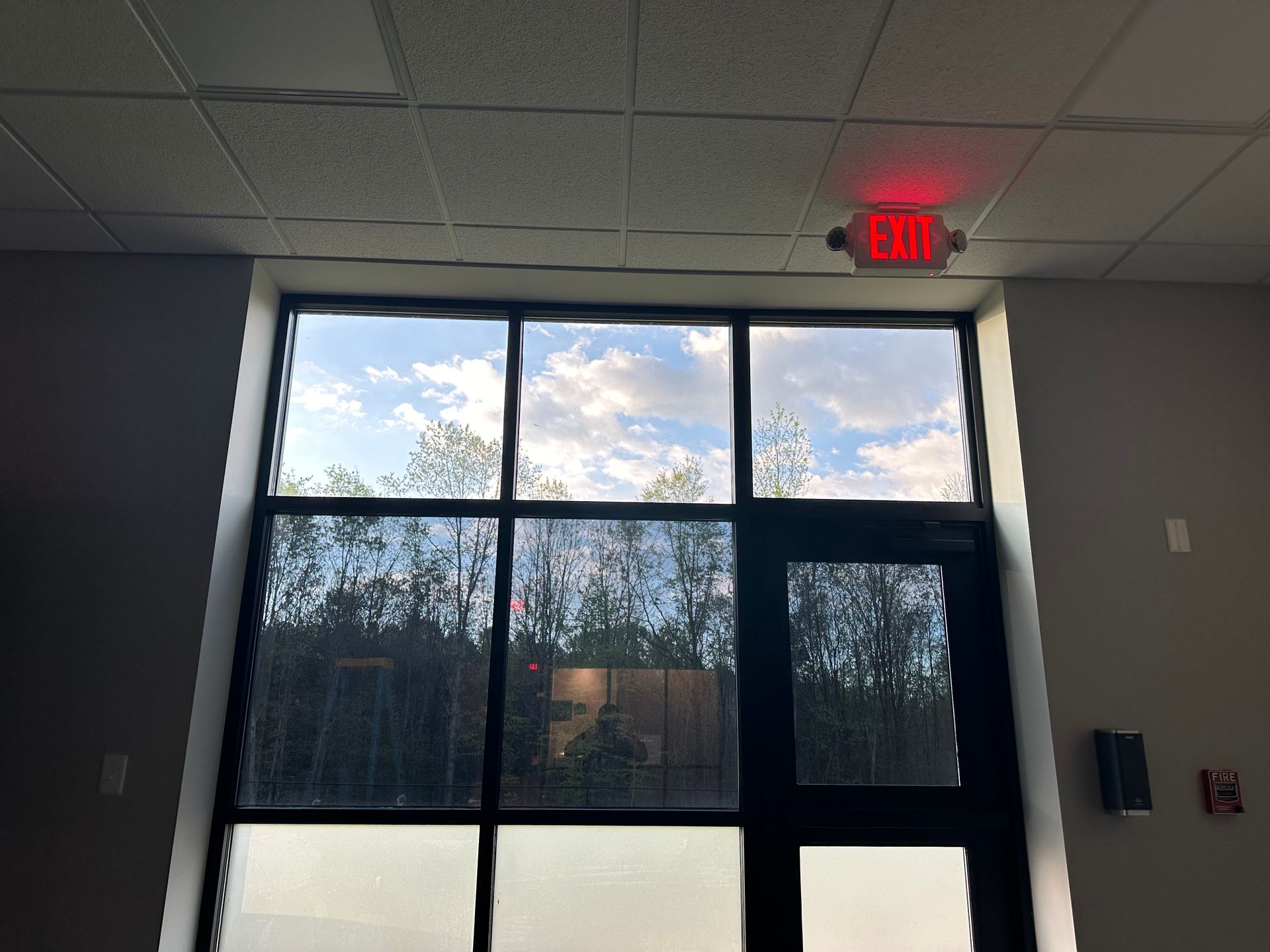 A red exit sign is above a large window