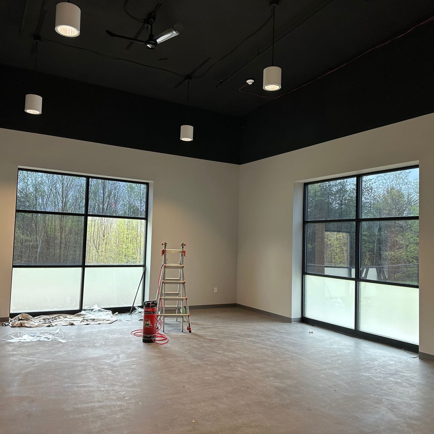 An empty room with lots of windows and a ladder