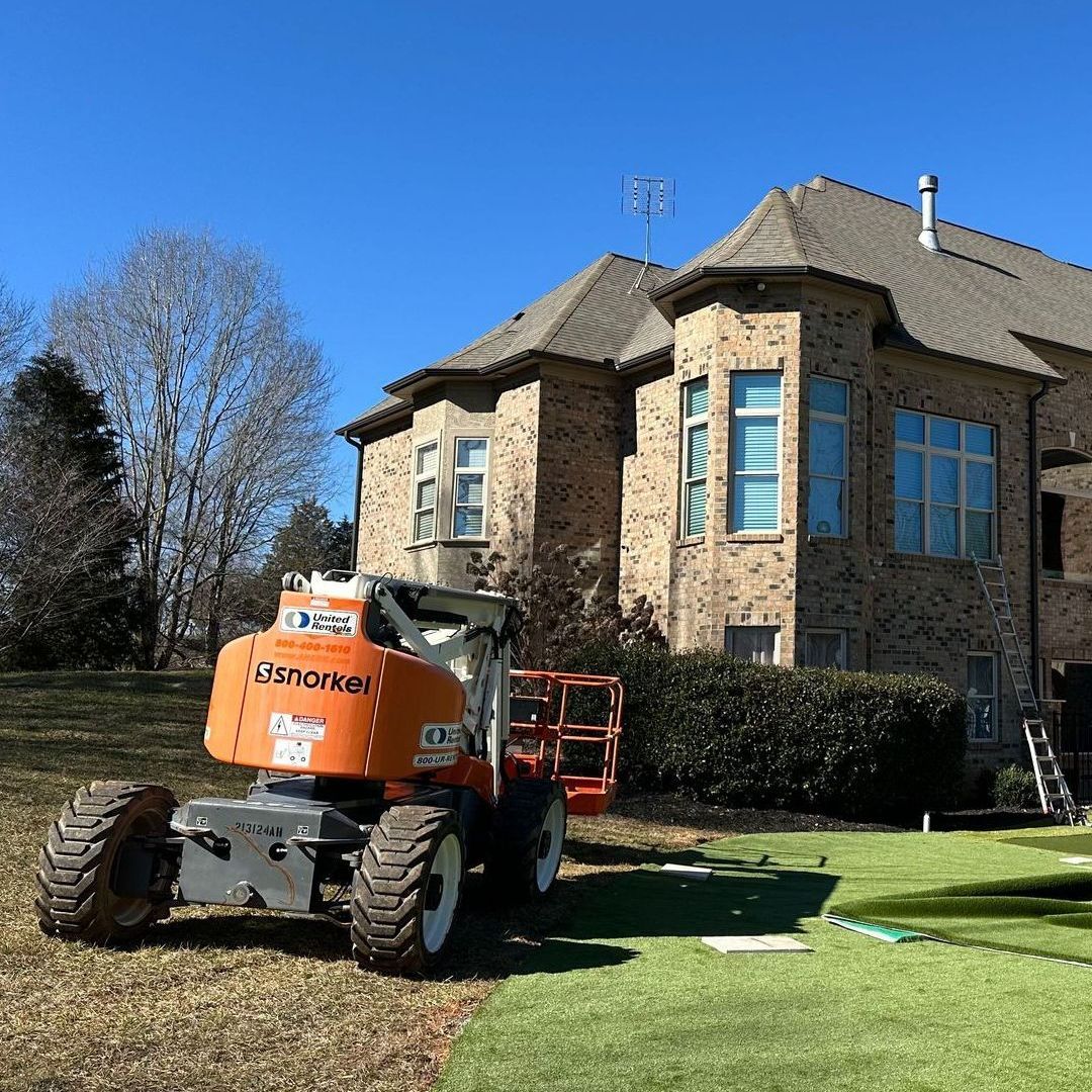 A tractor is parked in front of a large brick house.
