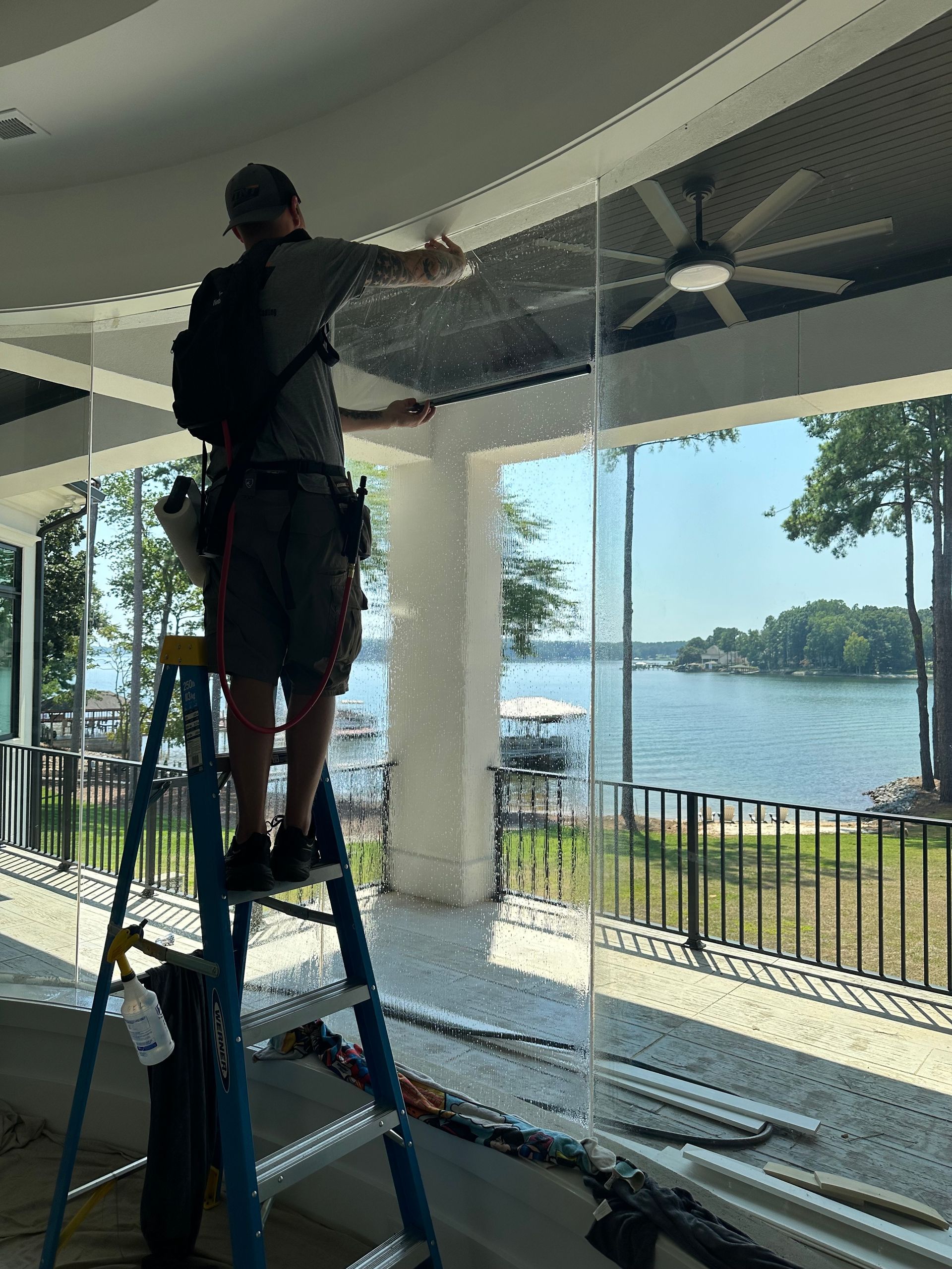A man is standing on a ladder working on a ceiling fan.