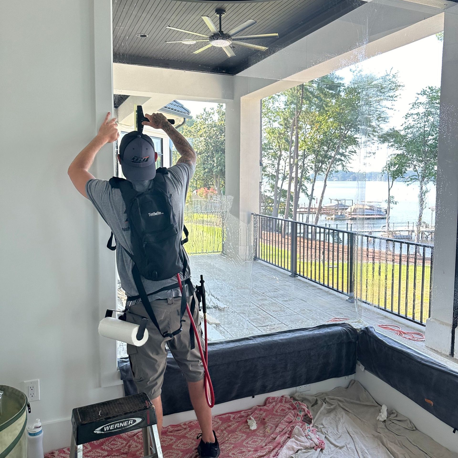 A man is standing on a ladder cleaning a window.