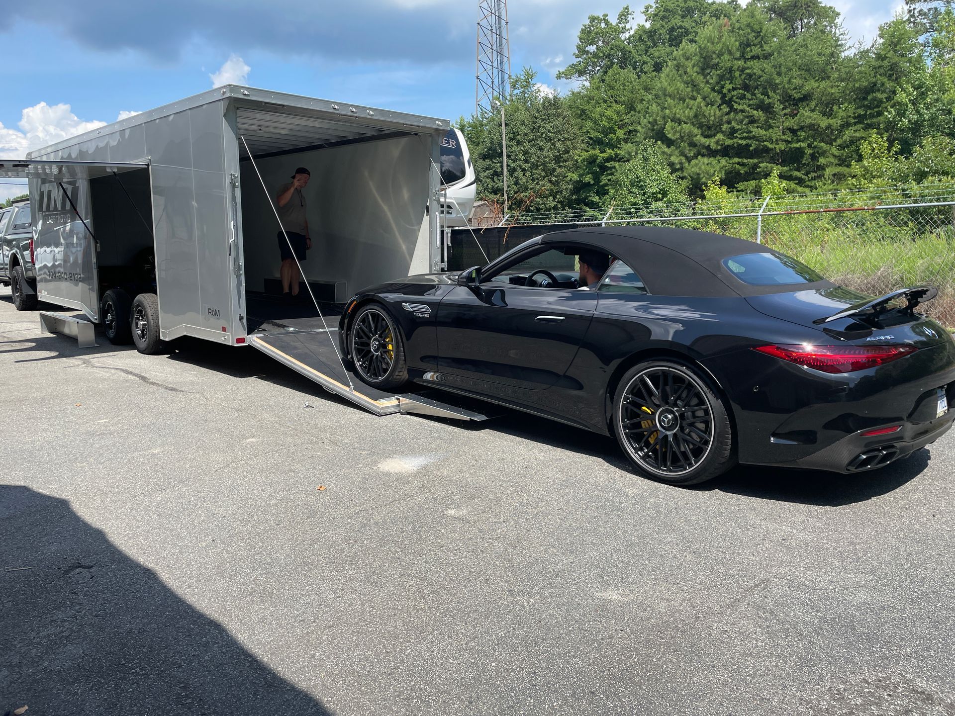 A black sports car is being towed by a trailer.