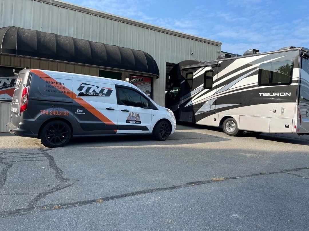 A van and a rv are parked in front of a building.