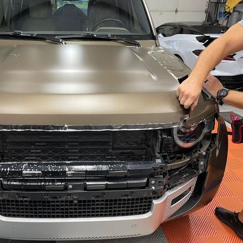 A man is sitting on a chair working on a car.