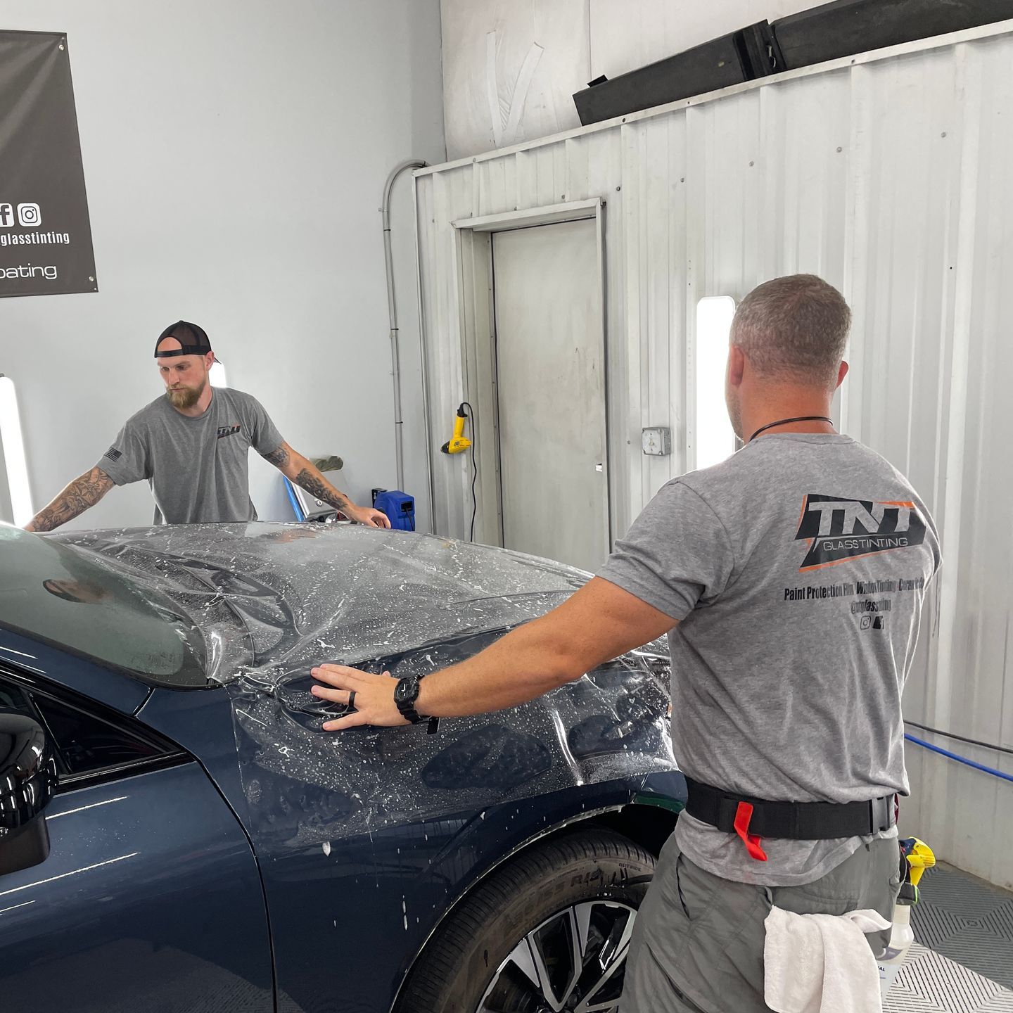 Two men are working on a car in a garage.