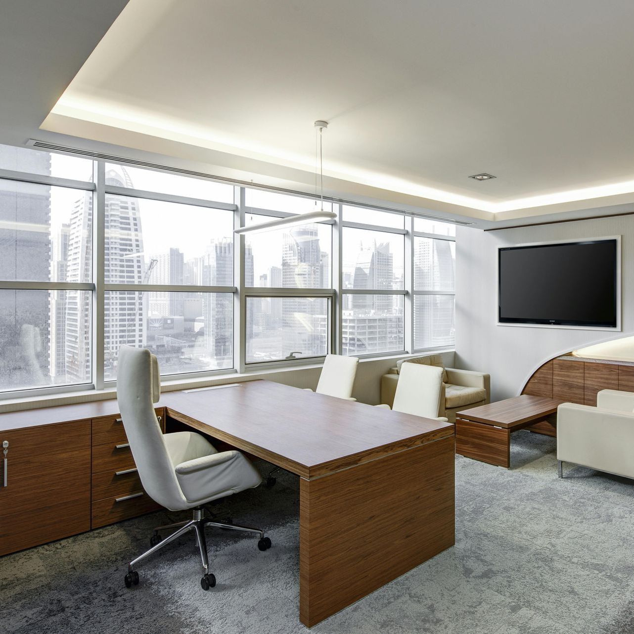 A room with a desk and chairs and a flat screen tv