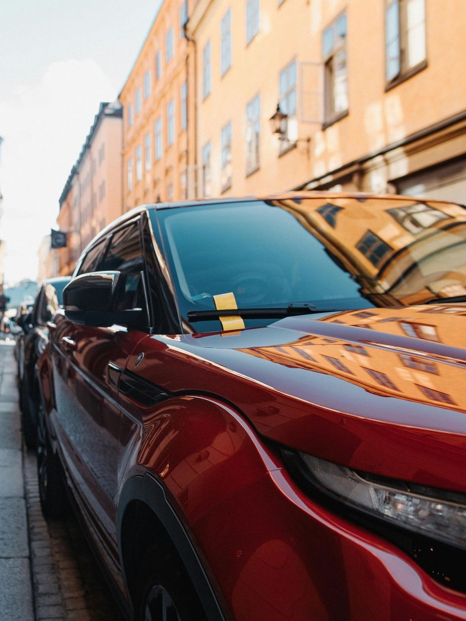 A red car is parked on the side of the road