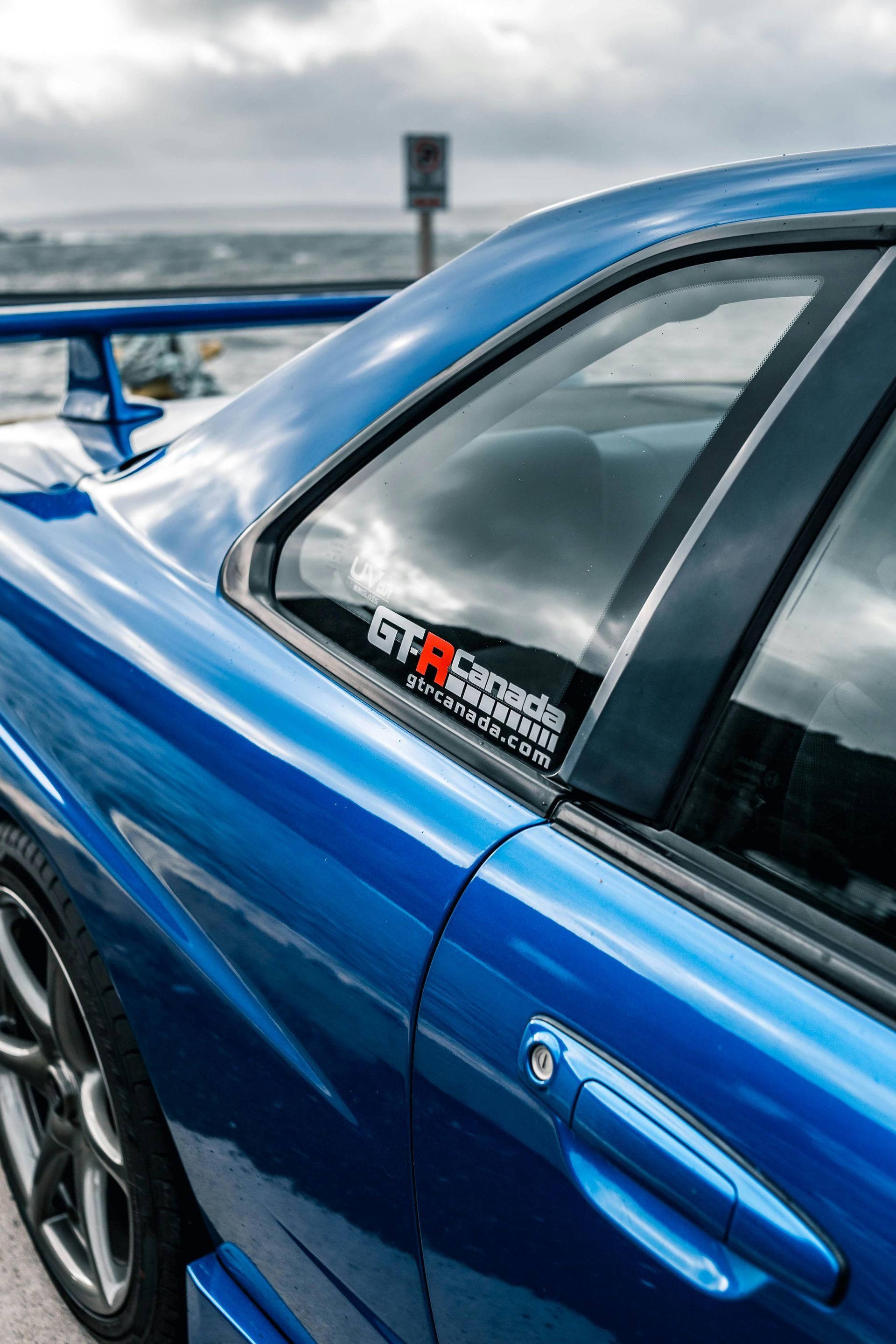 A close up of a blue car with a sticker on the window.