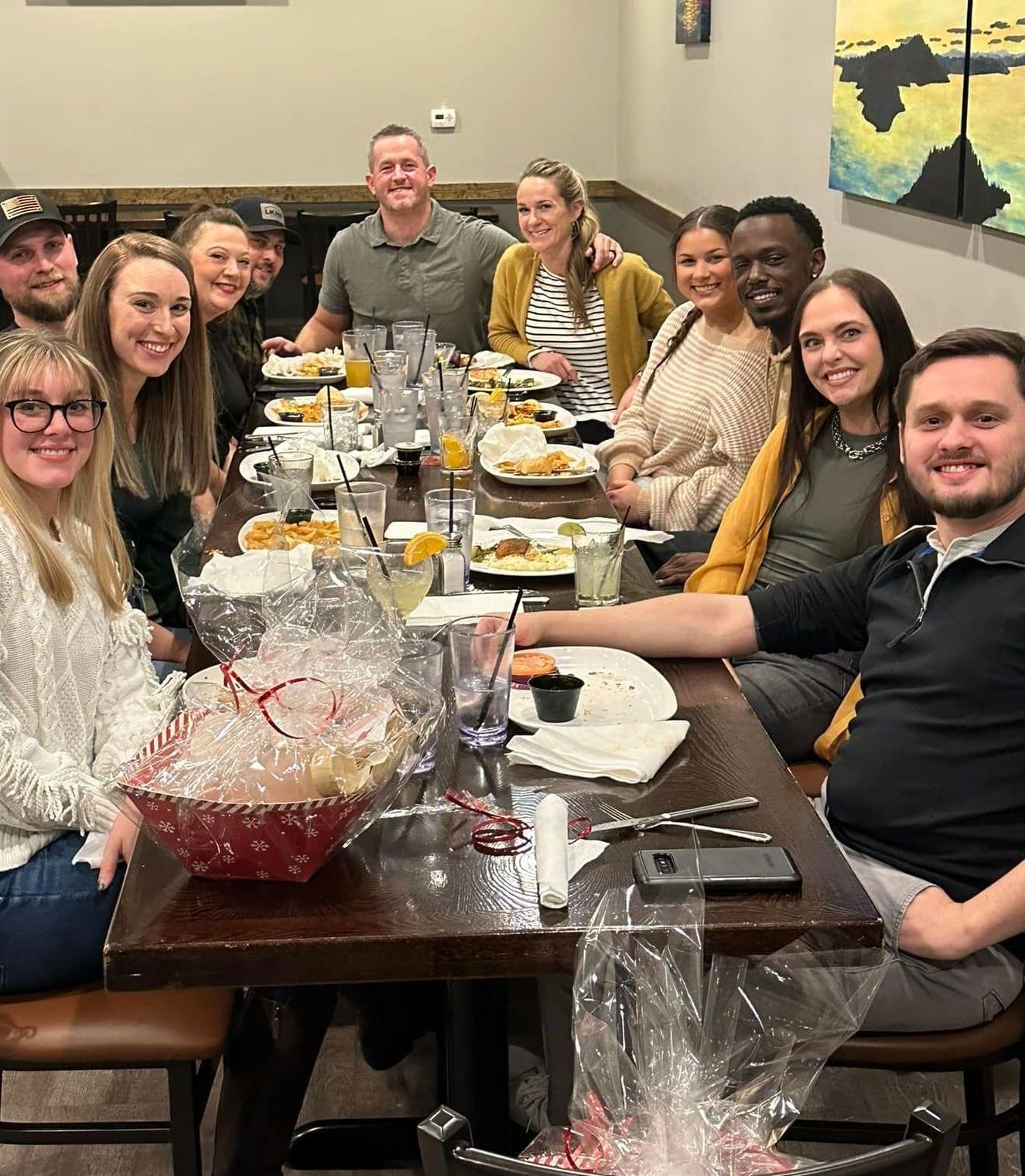 A group of people are sitting at a long table with plates of food.