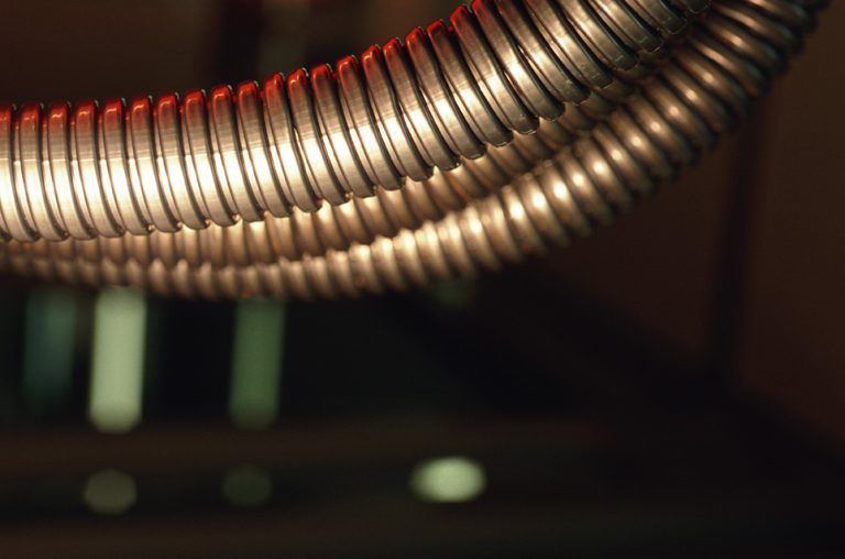 A close up of a metal hose with a dark background