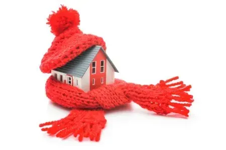 A small house is wrapped in a red scarf and hat.