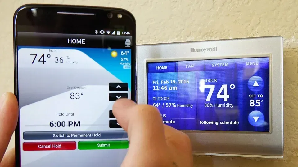 A person is using a smart phone to control a thermostat.
