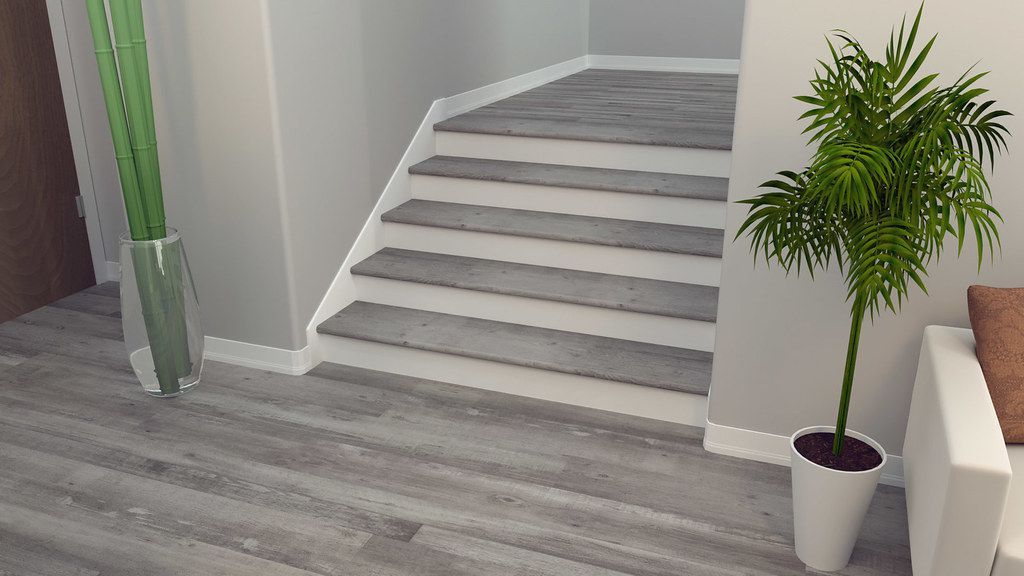 A potted plant is sitting next to a set of stairs in a living room