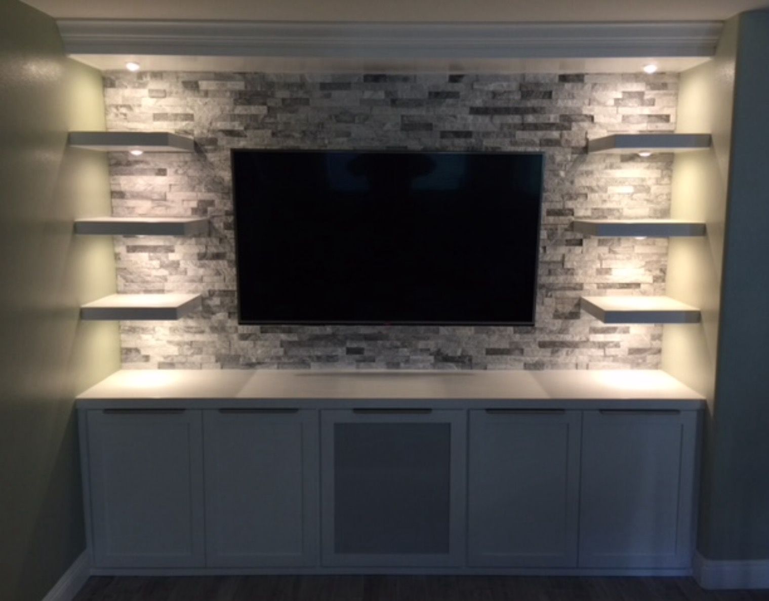 A flat screen tv is mounted to a brick wall in a living room