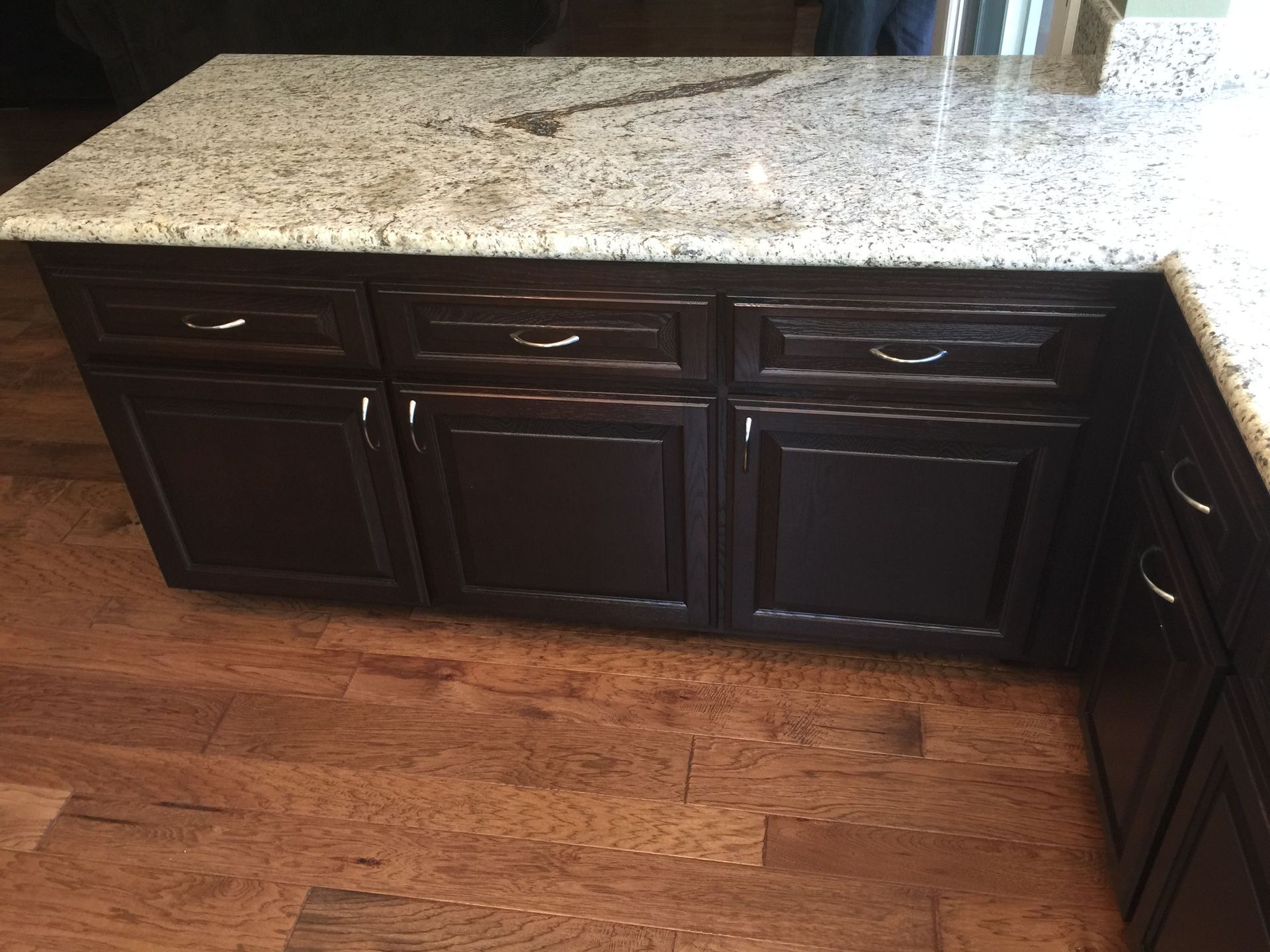 A kitchen with dark cabinets and a granite counter top
