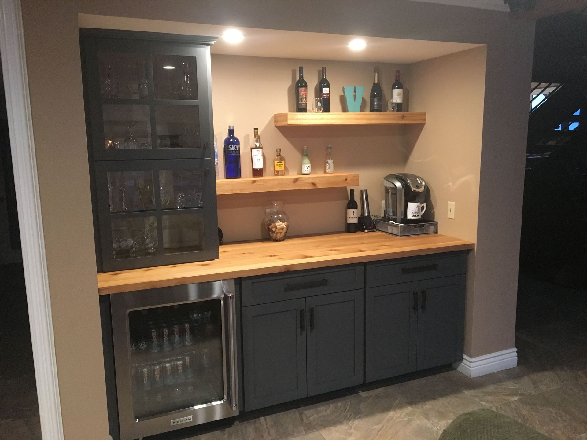 A bar with bottles of wine on shelves and a refrigerator