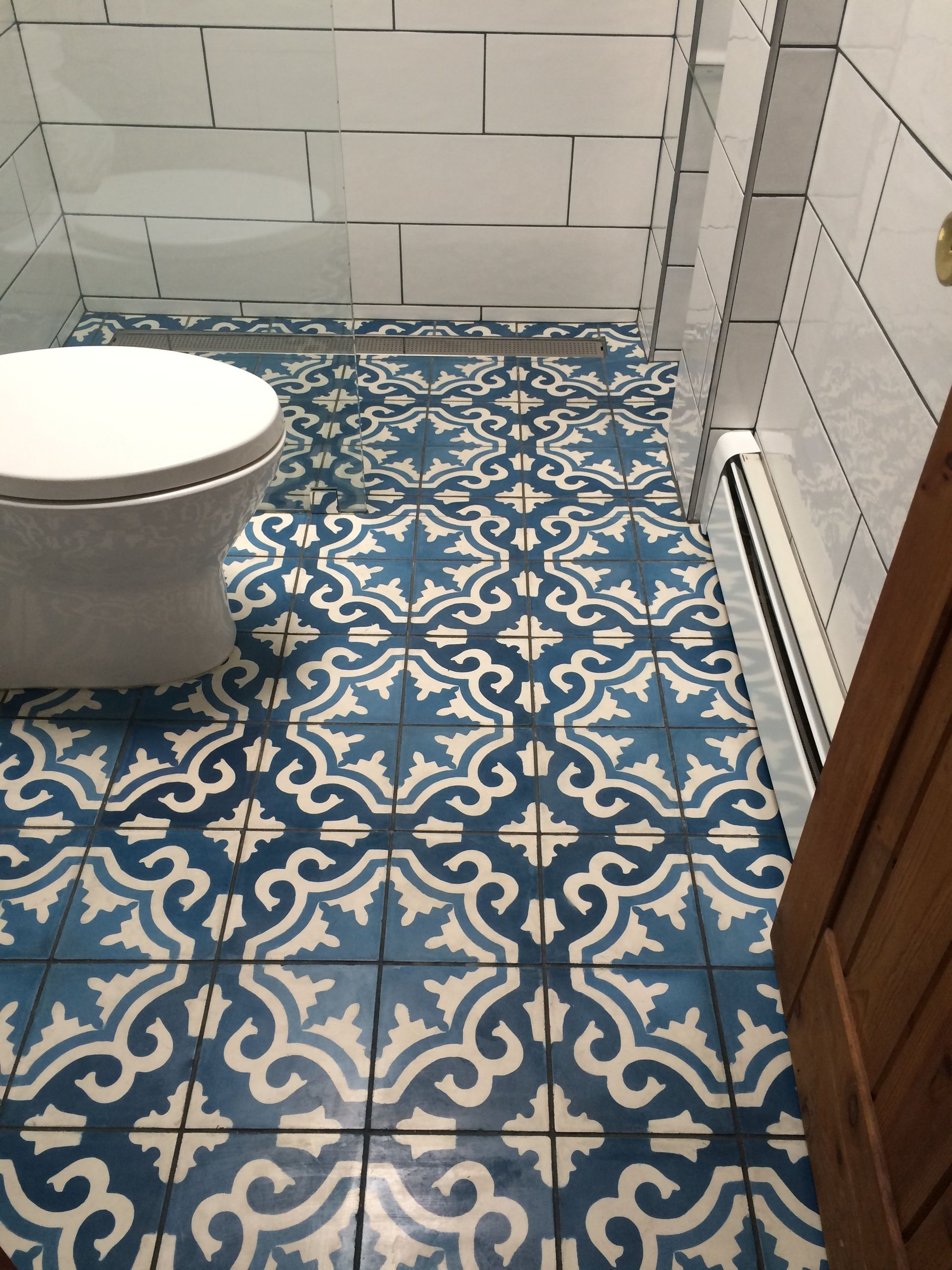 A bathroom with blue and white tiles and a toilet