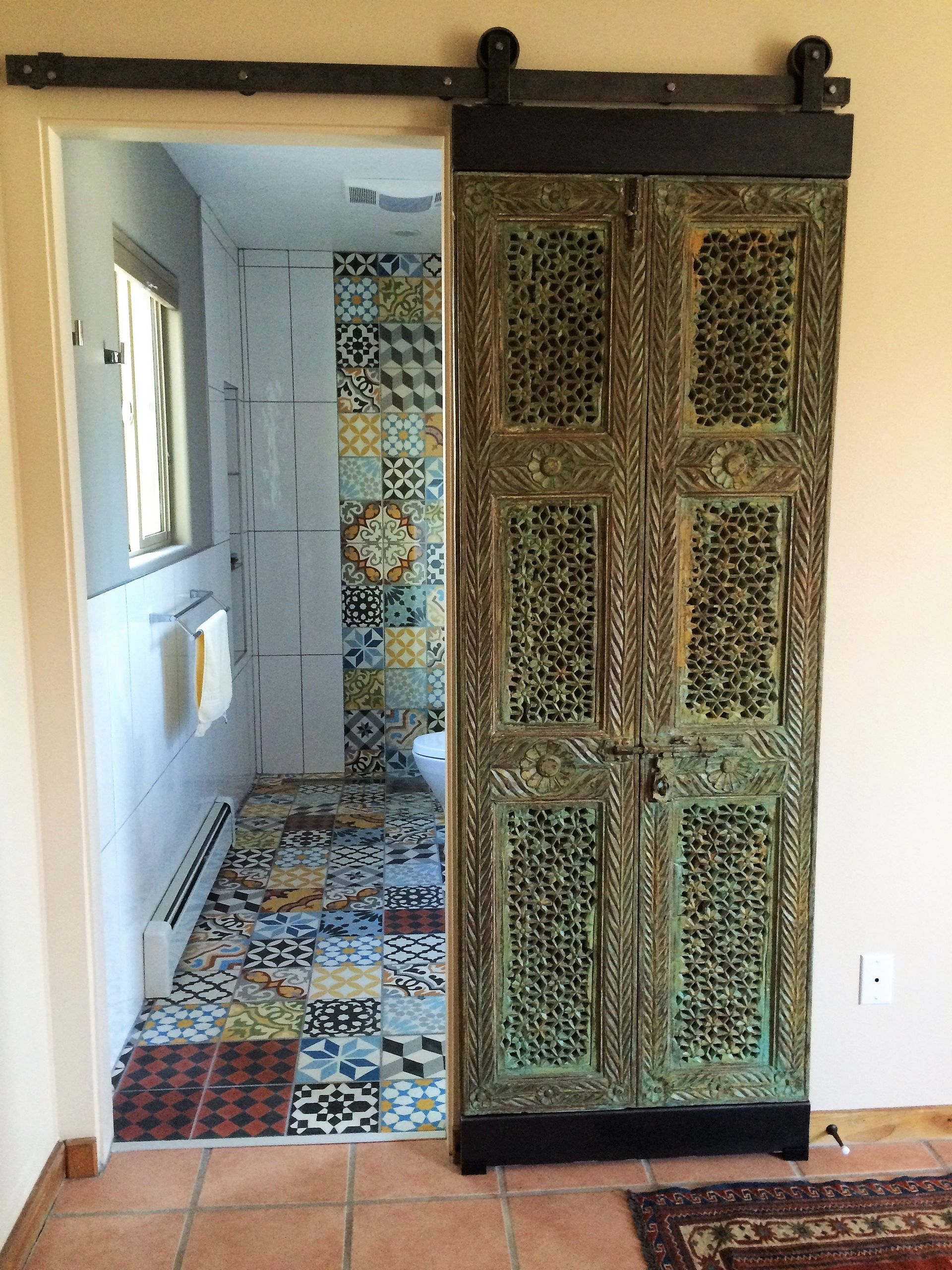 A bathroom with a sliding barn door leading to it.
