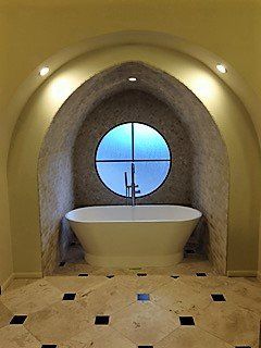 A bathroom with a bathtub and a round window.