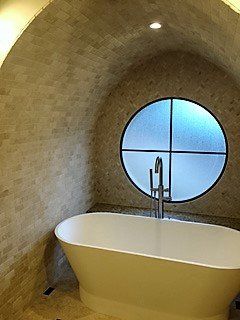 A bathroom with a bathtub and a round window.