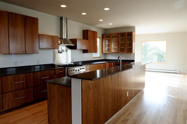 An empty kitchen with wooden cabinets and black counter tops
