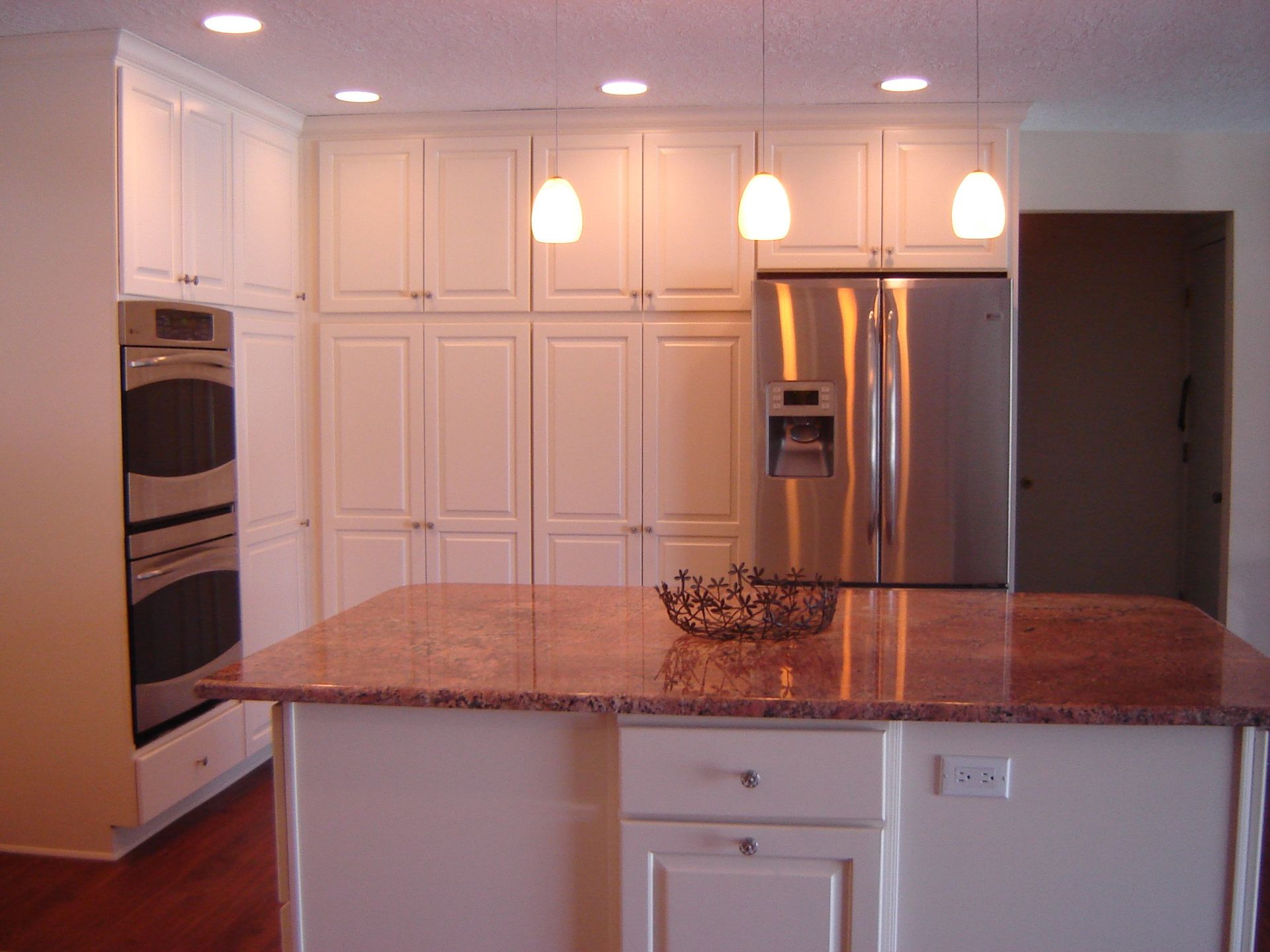 A kitchen with white cabinets and a stainless steel refrigerator