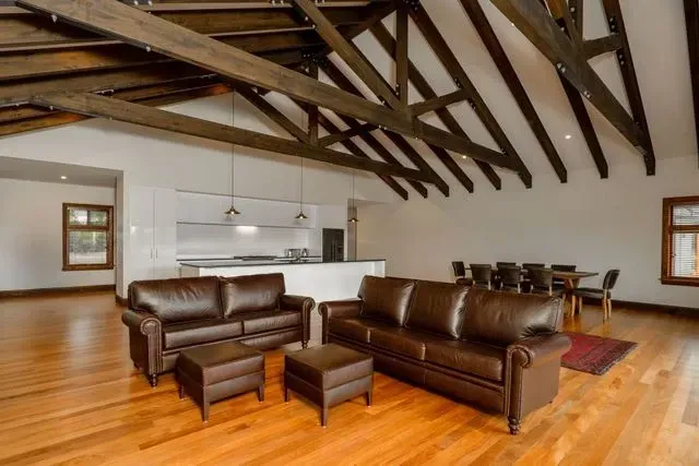A living room with a couch , chairs , ottoman and table.