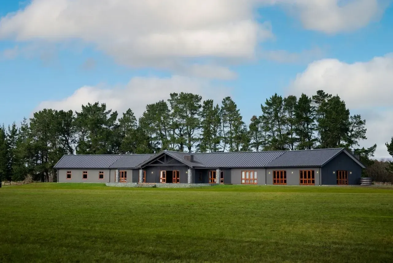 A large house sits in the middle of a lush green field