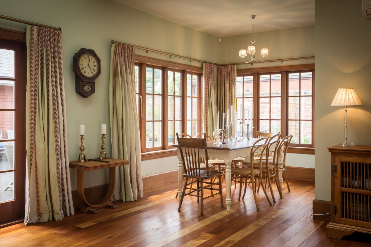 A dining room with a table and chairs and a clock on the wall.
