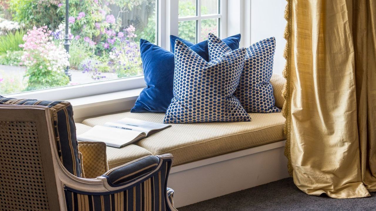 A window seat with blue pillows and a chair in a living room.