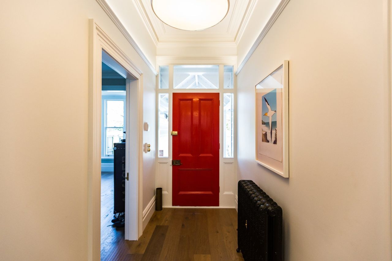 A hallway with a red door and a picture on the wall.