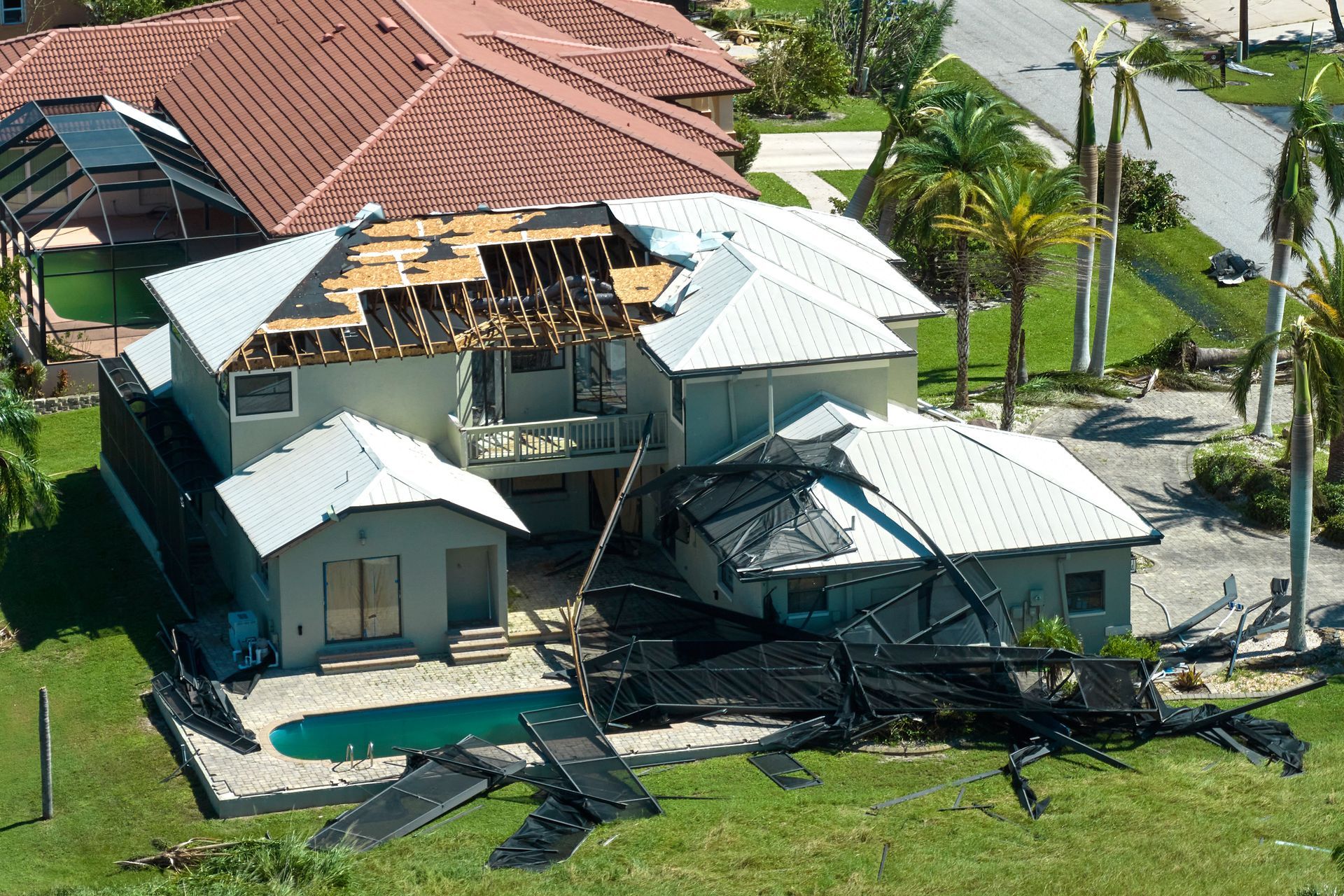 House with roof damage from a storm, pool in front, debris scattered. House with roof damage from a storm, pool in front, debris scattered.