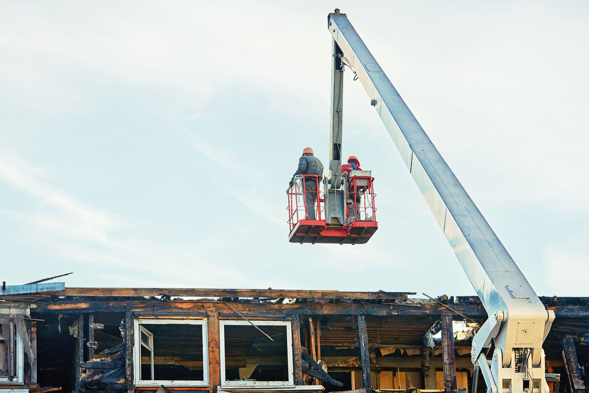 Workers in a lift inspecting a damaged building after a fire. Workers in a lift inspecting a damaged building after a fire.