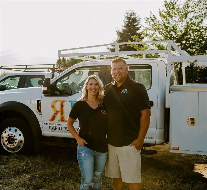 Man and woman stand by a white work truck with logo, smiling. Outdoors, sunny. Man and woman stand by a white work truck with logo, smiling. Outdoors, sunny.