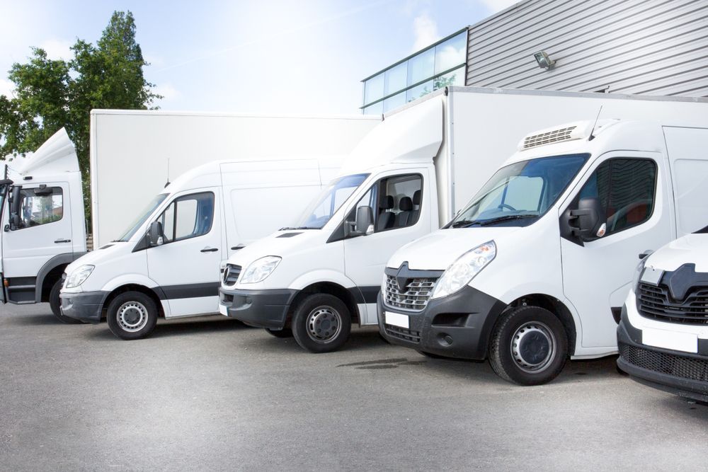 Row of White Delivery Vans Parked Outside a Warehouse — Forster Smash Repairs in Forster, NSW