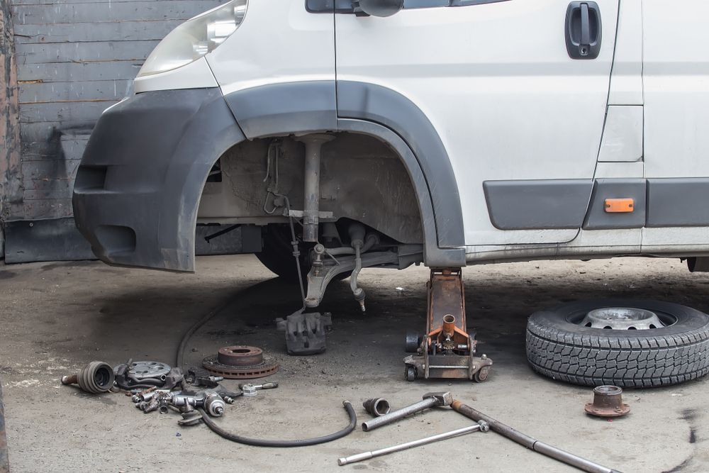 Silver SUV Raised on Jacks With Front Wheel Removed in a Garage — Forster Smash Repairs in Forster, NSW