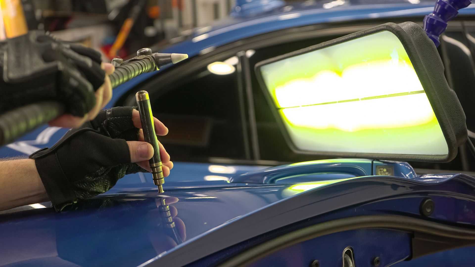 Gloved Hand Using a Tool on a Blue Car Body in an Auto Repair Shop — Forster Smash Repairs in Forster, NSW